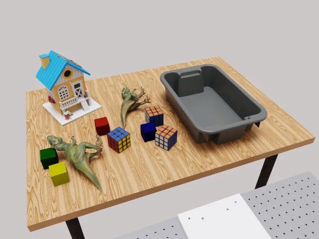 RoboLab scene: a tabletop with a toy house, blocks and a grey bin for the CleanUpToys task.