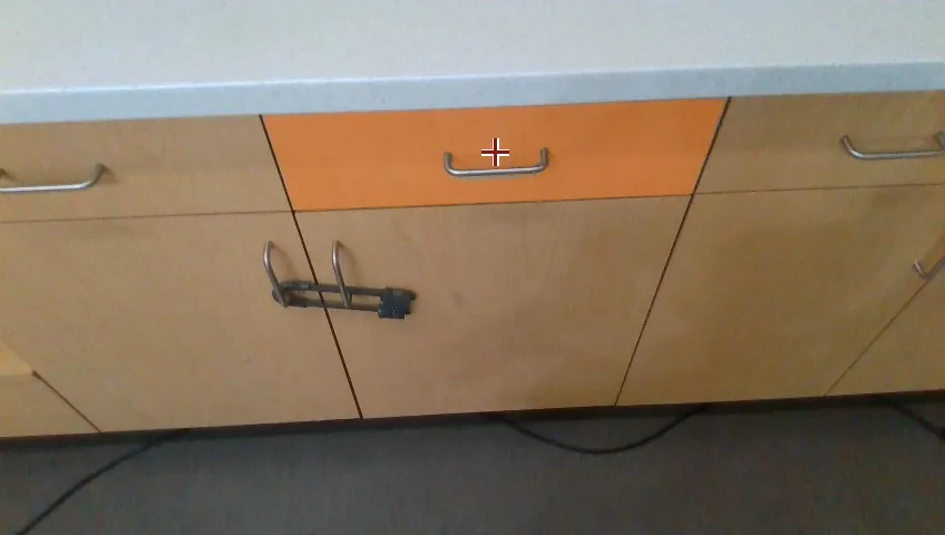 Ego view: a row of wooden cabinet fronts with the target drawer panel highlighted orange and a crosshair on its metal handle
